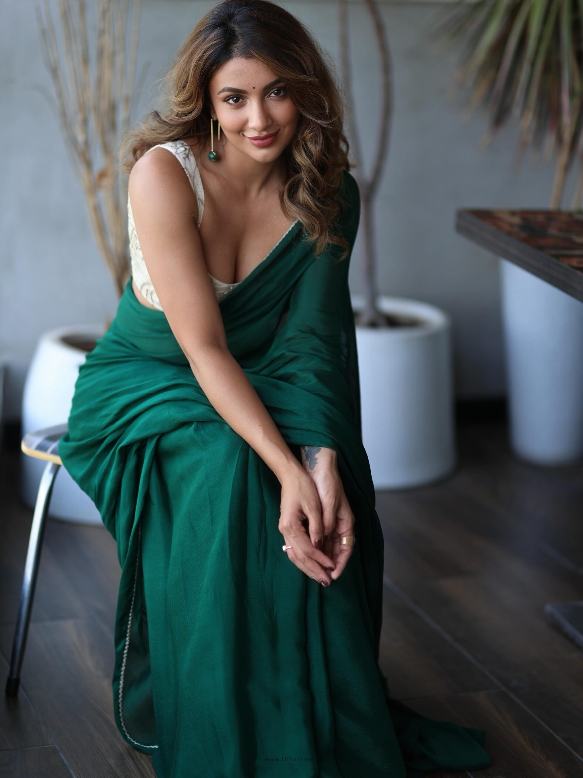 Tejaswi Madivada posing gracefully in a striking black saree paired with a deep low cut sleeveless velvet blouse and long hanging earrings.