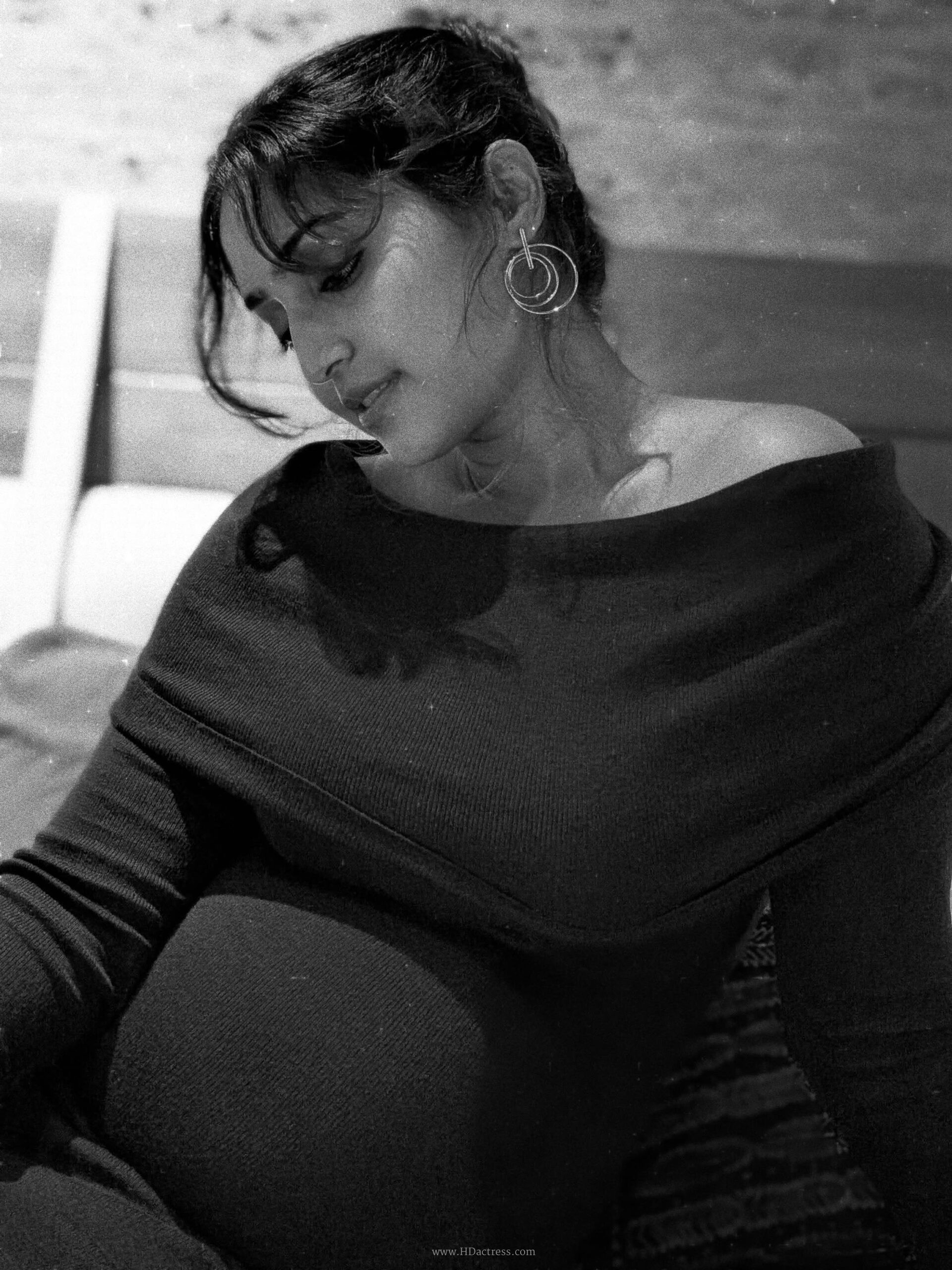 Close up of actress Reba Monica John smiling and holding her pregnant belly against a beautiful sunset backdrop.