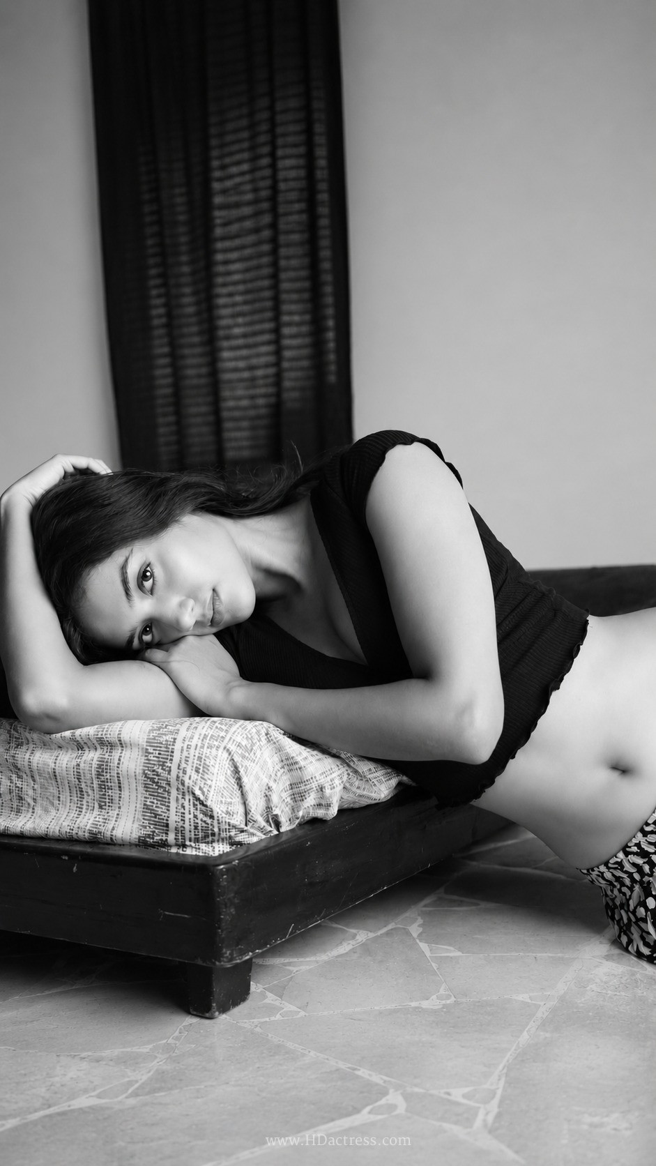 Actress Bhagyashri Borse posing confidently in a chic black v-neck crop top and matching high-waisted skirt.