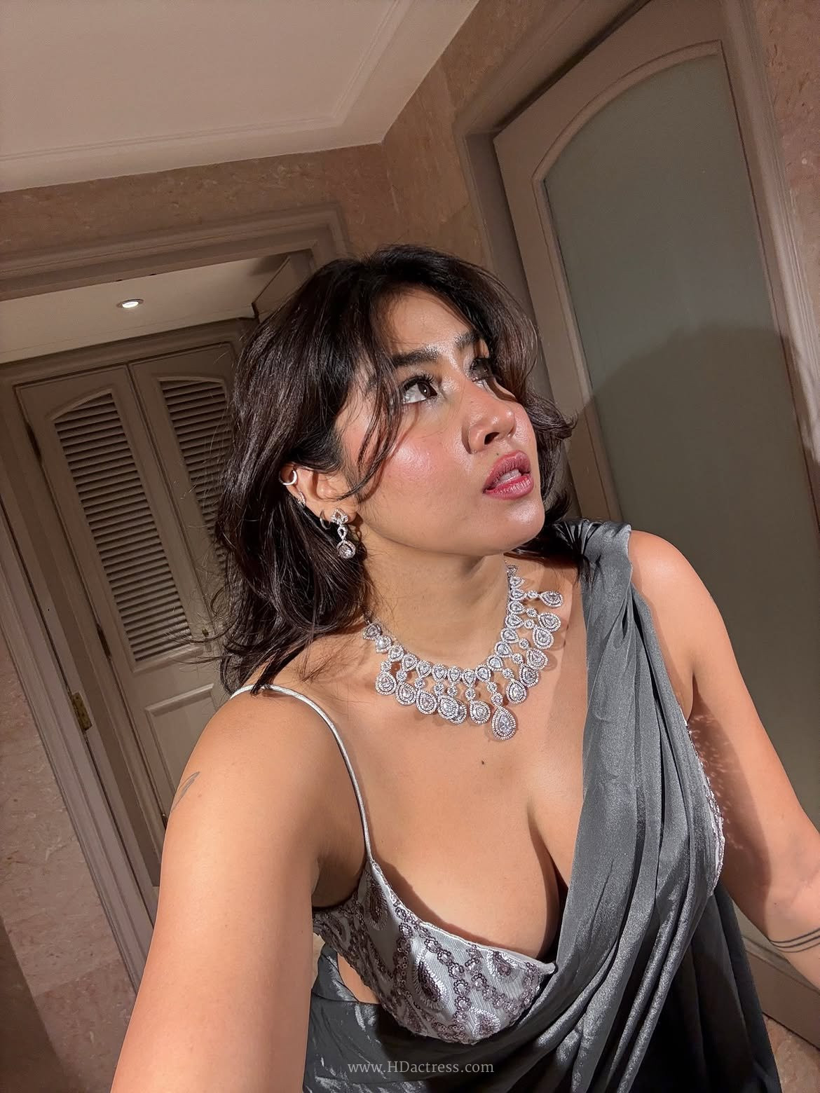 Sofia Ansari posing gracefully in a deep maroon plunging neckline traditional bra blouse paired with a gold lehenga skirt.