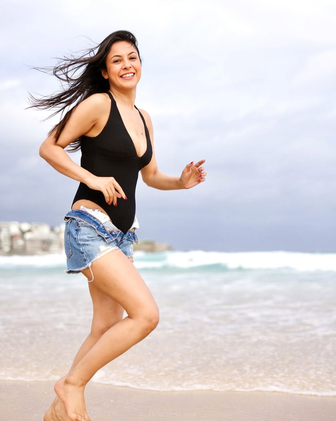 Shehnaaz Gill flaunting her fit physique in a sexy black one-piece swimsuit with a plunging deep V-neckline on the beach.
