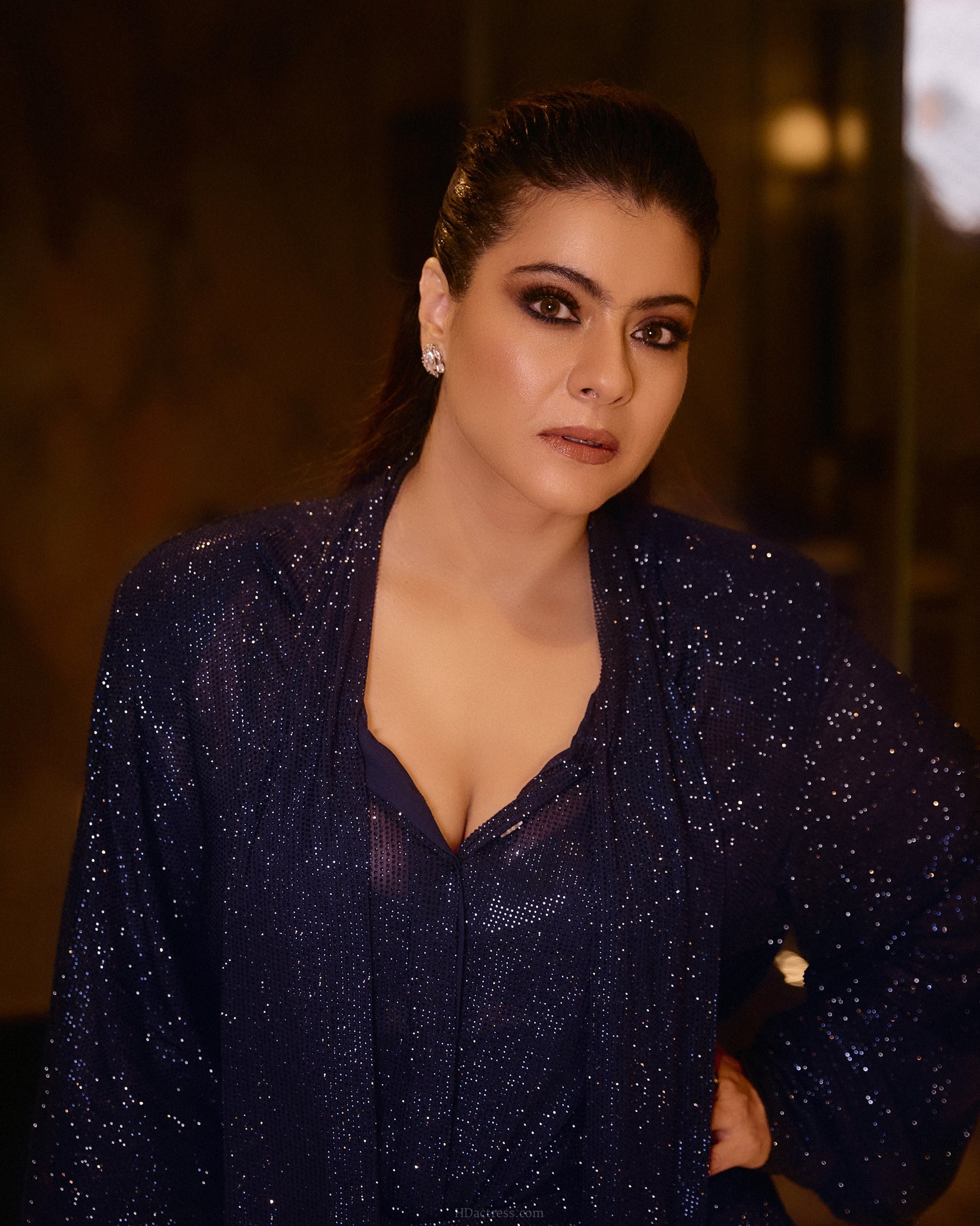 Bollywood actress Kajol Devgan flaunting her curves in a tight-fitting shimmering green sequin pattern dress with a deep V-neckline.