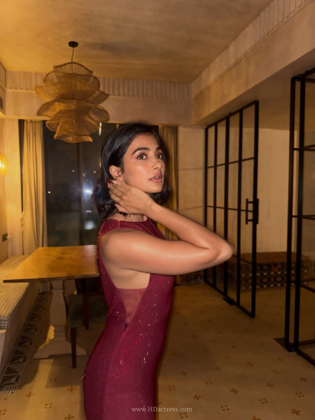 Close-up and full-length views of Pooja Hegde wearing a shimmering deep burgundy gown featuring an elegant sheer back panel.