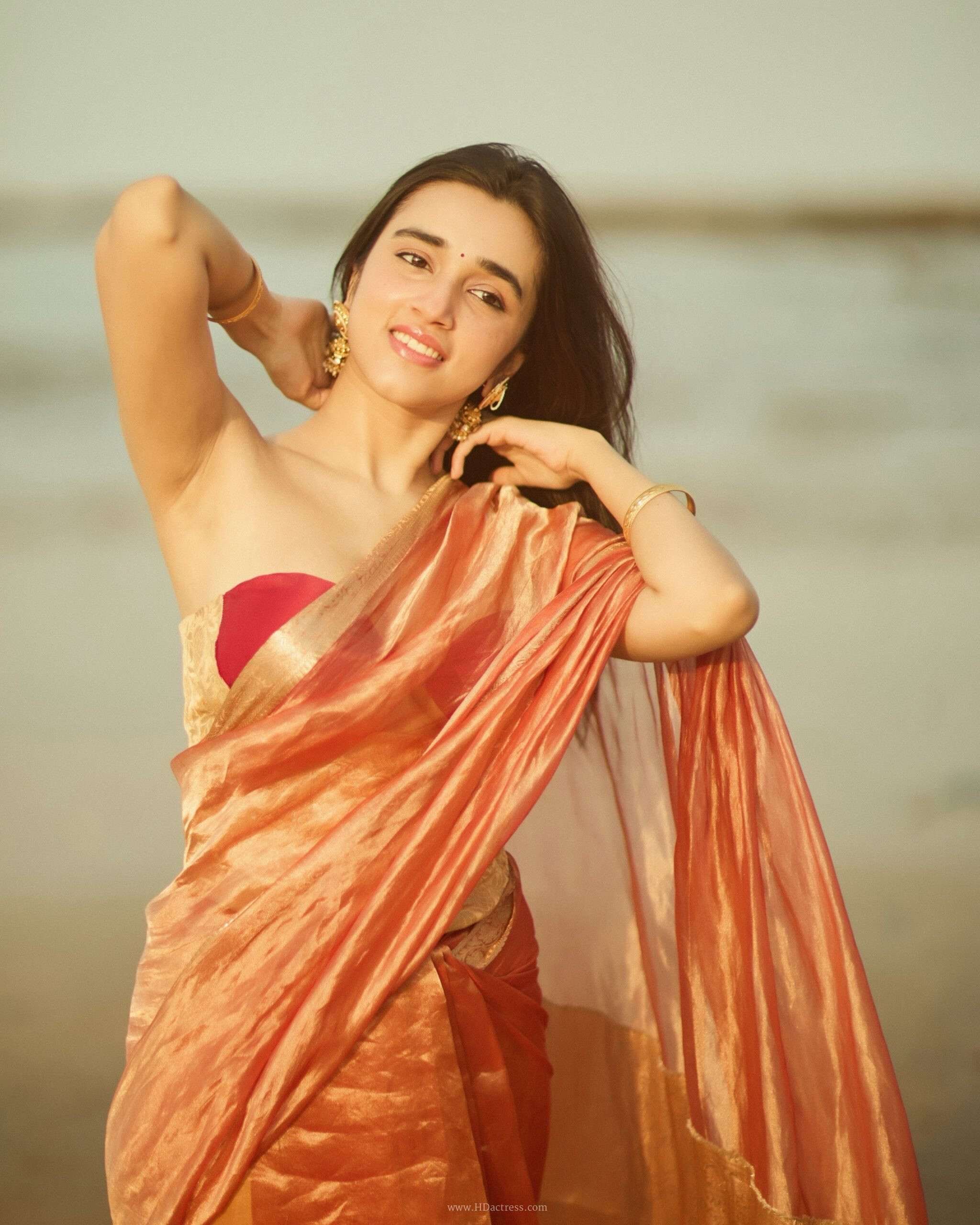 Nuveksha in orange silk saree with gold border