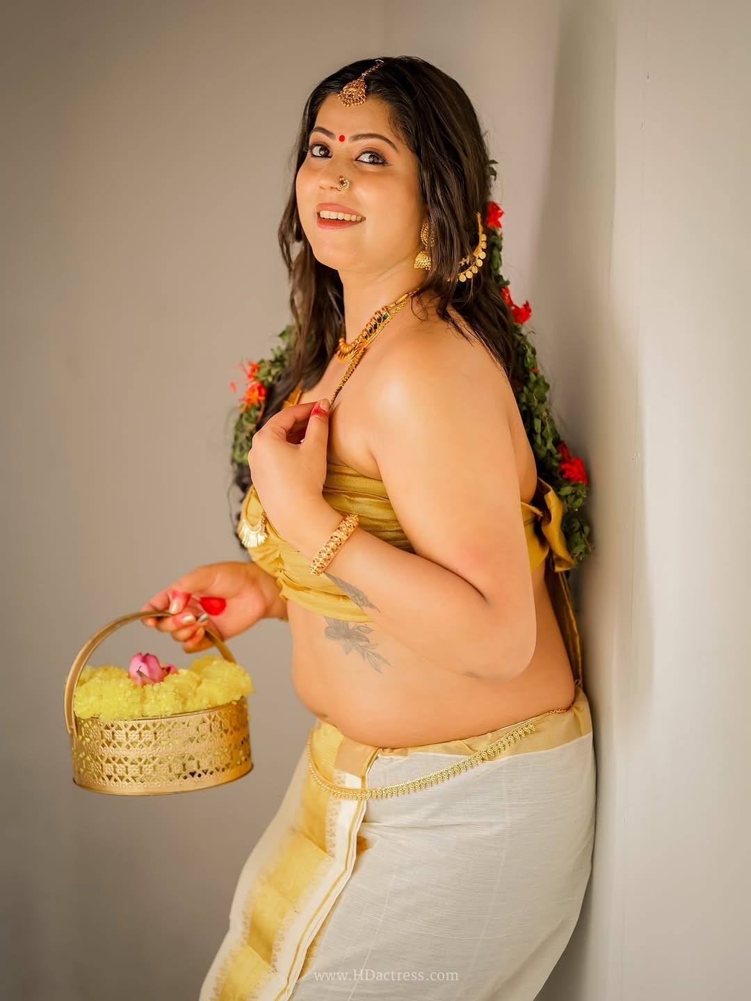 Selby Scaria Looks Gorgeous in Traditional Golden Kerala Kasavu Set - Image 7 `Selby Scaria holding flower basket ethnic look`