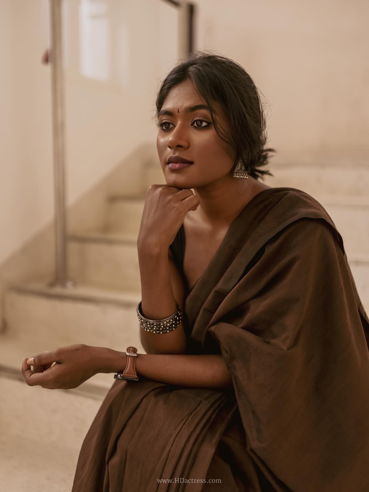 Thivyawathyy wearing a brown linen saree and black sleeveless blouse