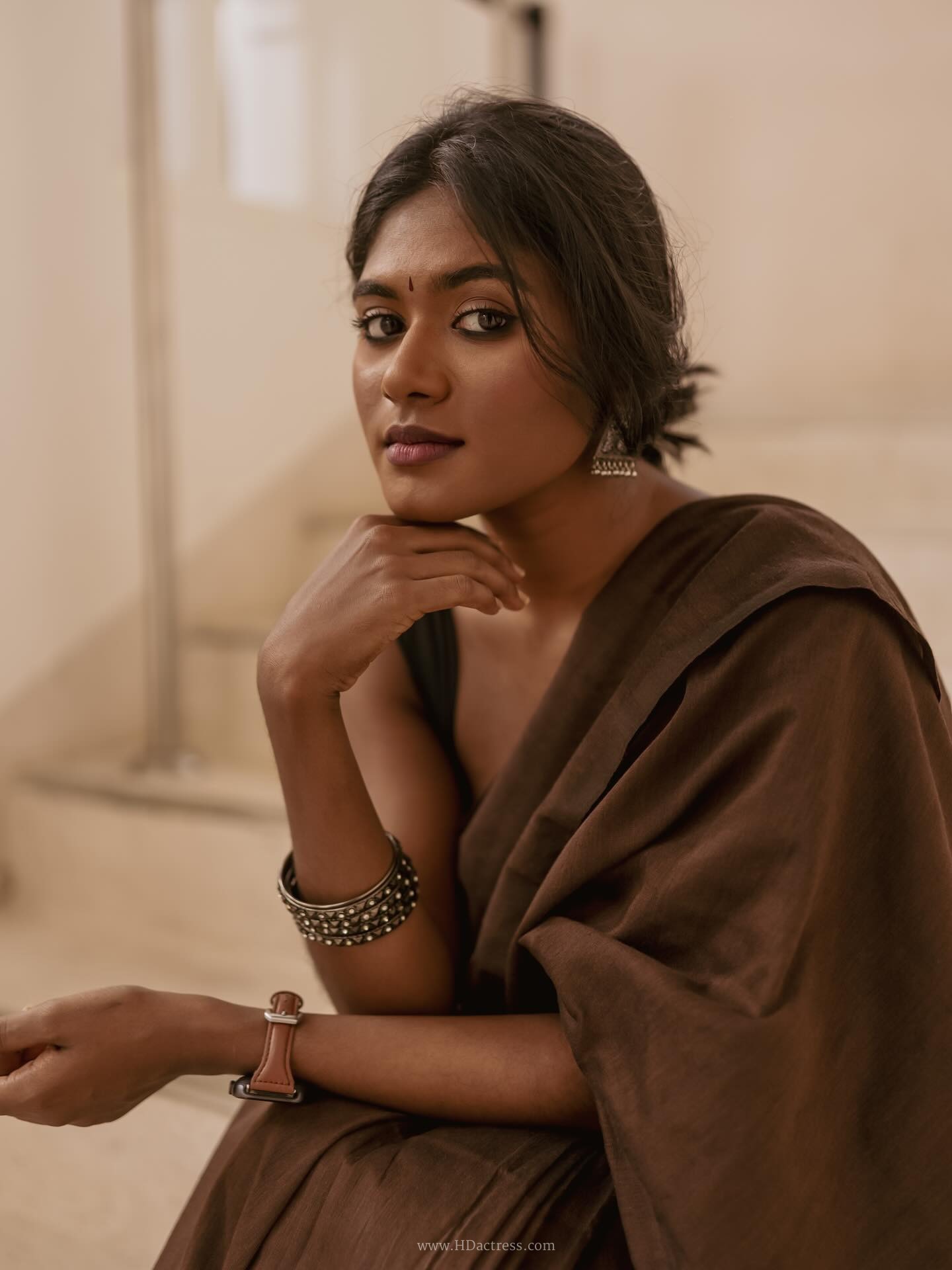 Thivyawathyy wearing a brown linen saree and black sleeveless blouse