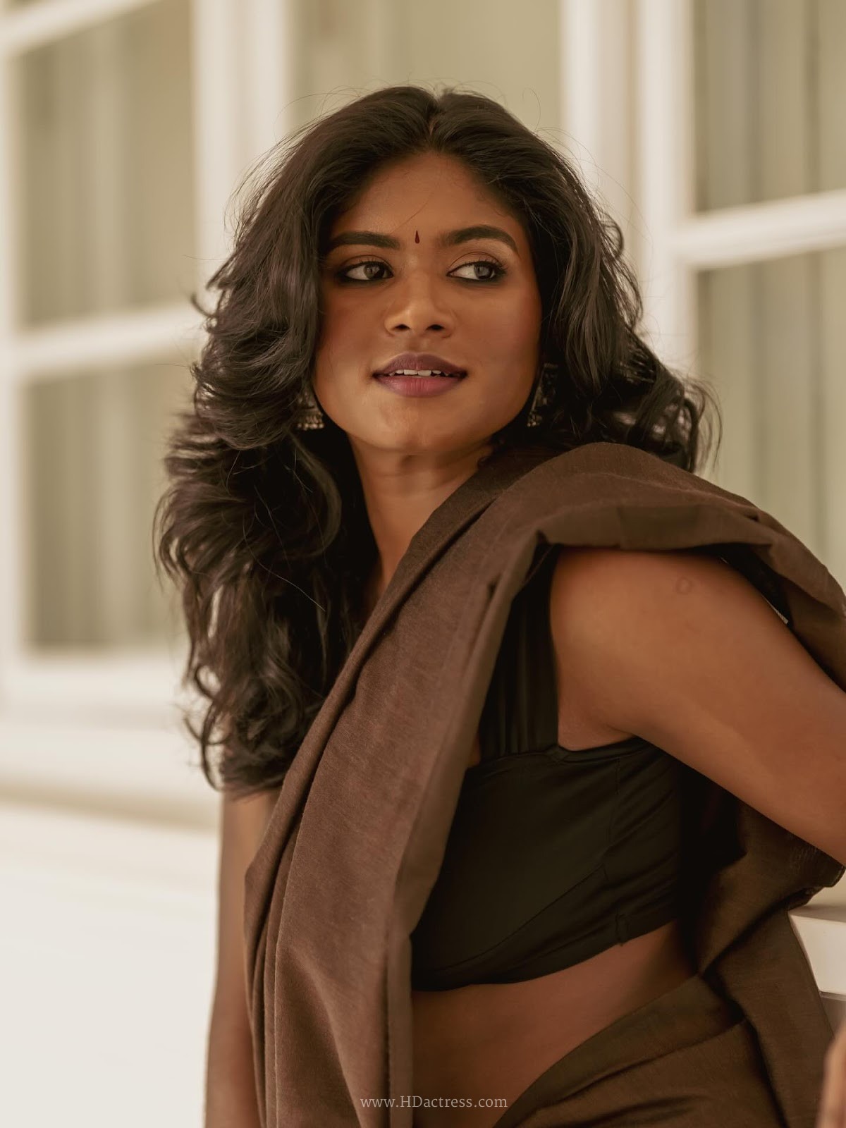 Thivyawathyy wearing a brown linen saree and black sleeveless blouse