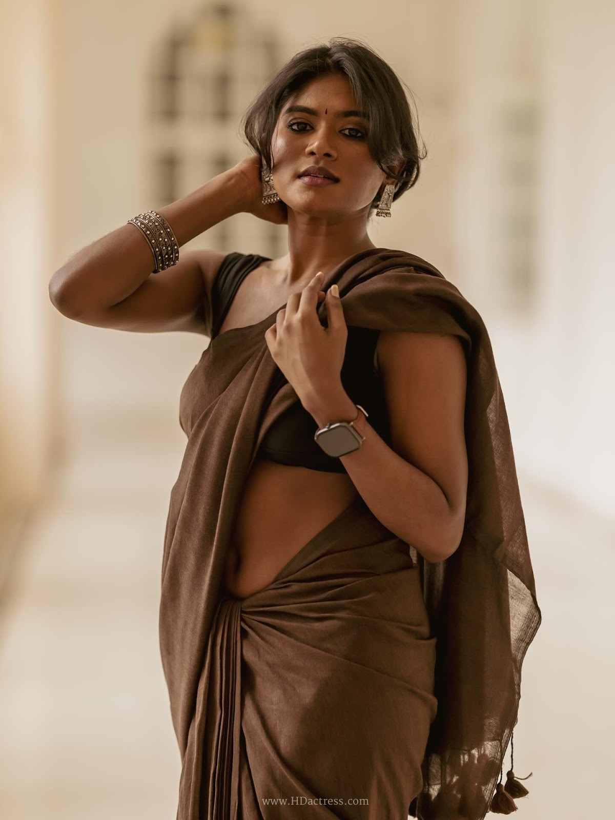 Thivyawathyy wearing a brown linen saree and black sleeveless blouse