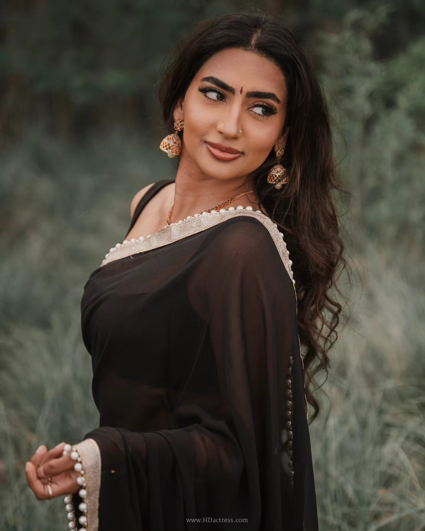 Vimzz K wearing a black chiffon saree and sleeveless blouse