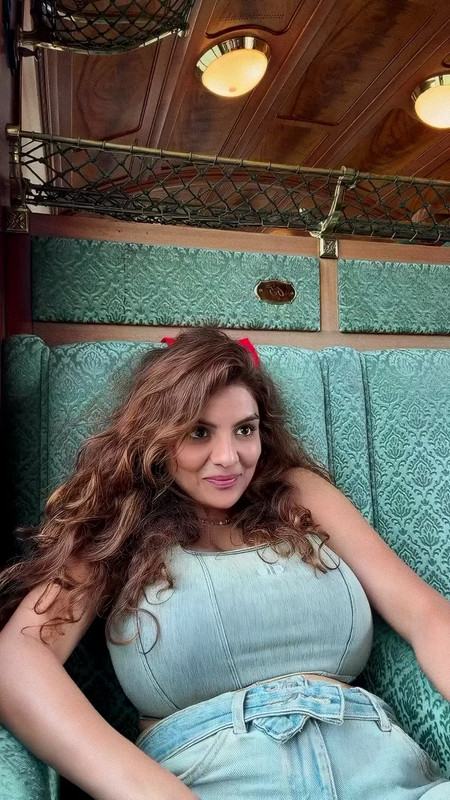 Anveshi Jain smiling in light blue denim crop top and jeans, midriff and cleavage on full display